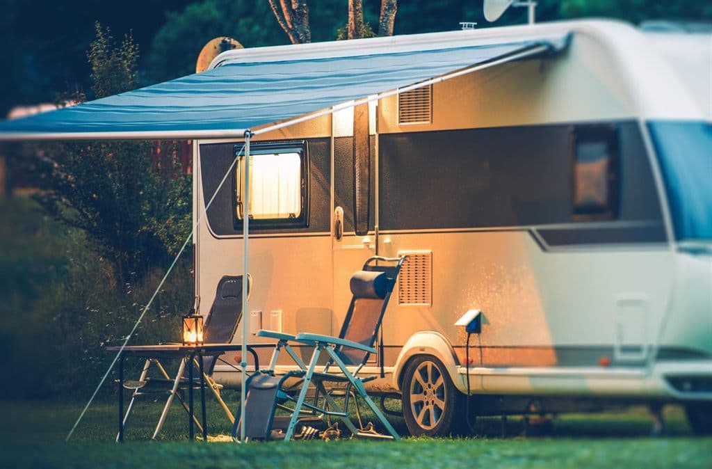 Caravana propia con toldo y mesa preparada al atardecer